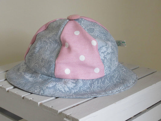 Kid's Sun Hat Made of Grey and White Floral Cotton Fabric with a Pink Polka Dot Insert and Pure White Lining with a Button Top Detail